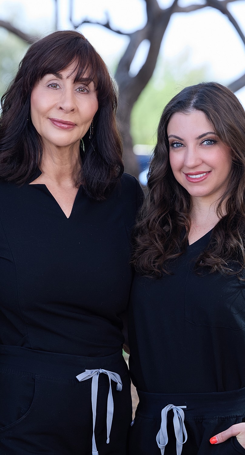 Two women in matching black outfits smiling.